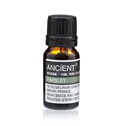 A small, brown glass bottle of “ANCIENT” brand Parsley essential oil stands on a white surface. Text on the label reads: "ANCIENT WISDOM / 10ML PURE ESSE PARSLEY PETROSELINUM CRISPUM ORIGIN: FRANCE FROM SEEDS AND HERBS PROCESS: STEAM DISTILL."