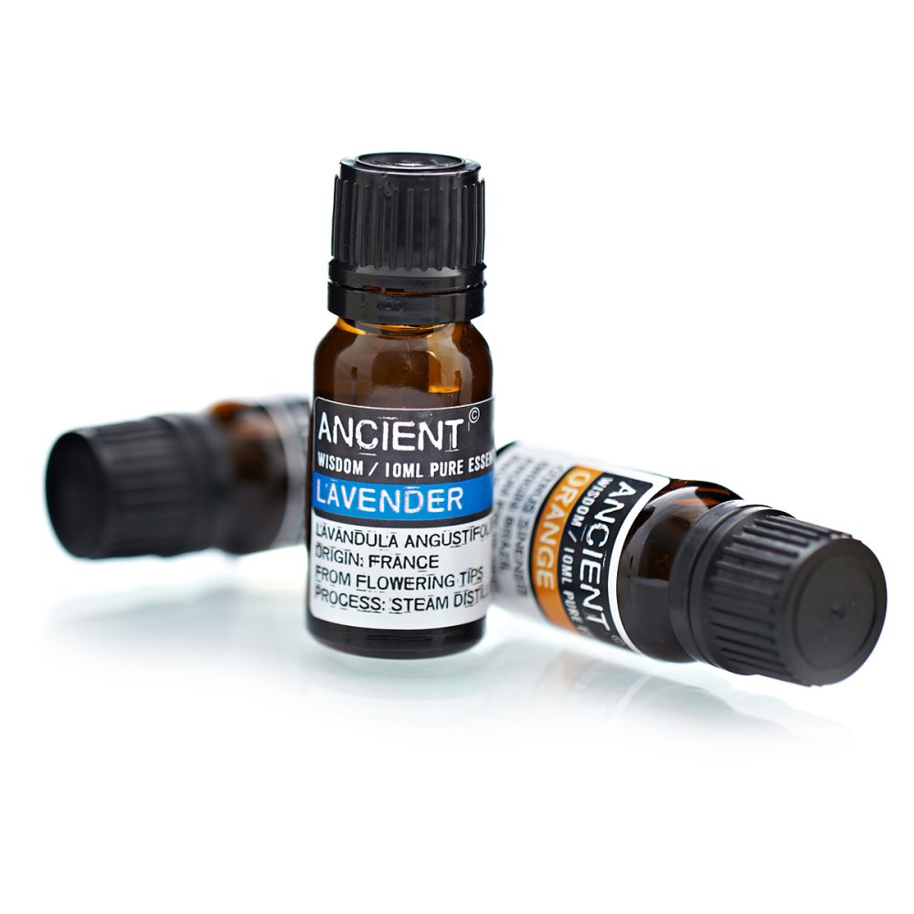 Amber bottles sit on a white surface. One label reads "ANCIENT WISDOM / 10ML PURE ESSEN LAVENDER LAVANDULA ANGUSTIFOL ORIGIN: FRANCE FROM FLOWERING TIPS PROCESS: STEAM DISTIL", and the other reads "ANCIENT WISDOM / 10ML PURE ORANGE"