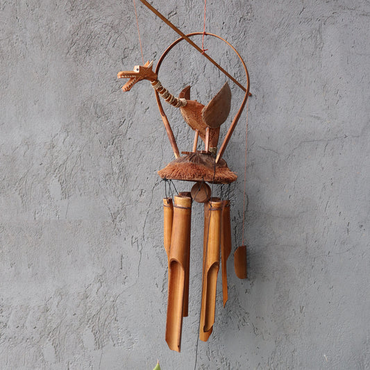 A wooden dragon-shaped wind chime hangs from a grey wall. The chime features bamboo tubes and coconut shell elements.