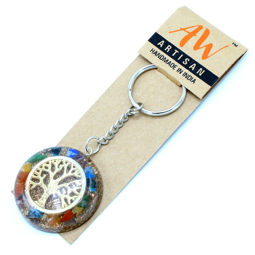 A "tree of life" keychain lays on a brown card, attached with a metal chain and ring. The card reads, "AW ARTISAN HANDMADE IN INDIA".