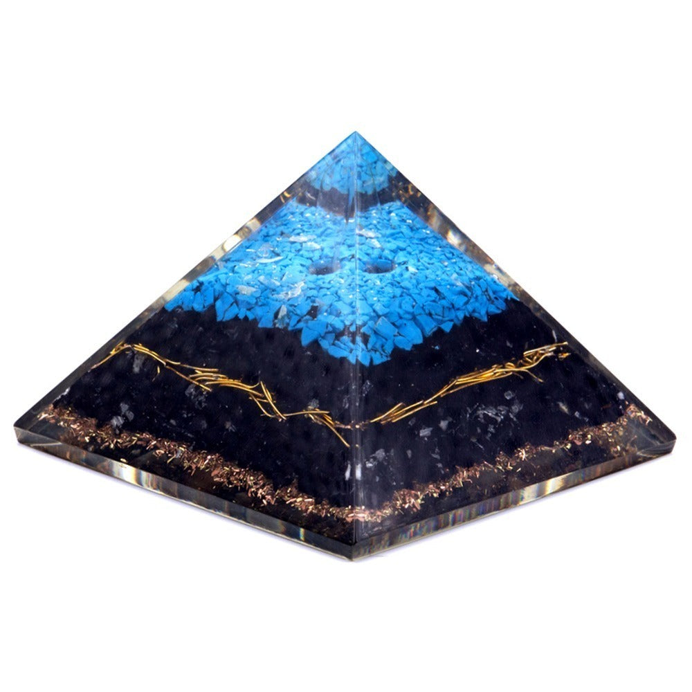 A clear, layered pyramid features copper-colored shavings at the base, a black middle with copper wire, and a top layer of blue stone fragments against a white background.