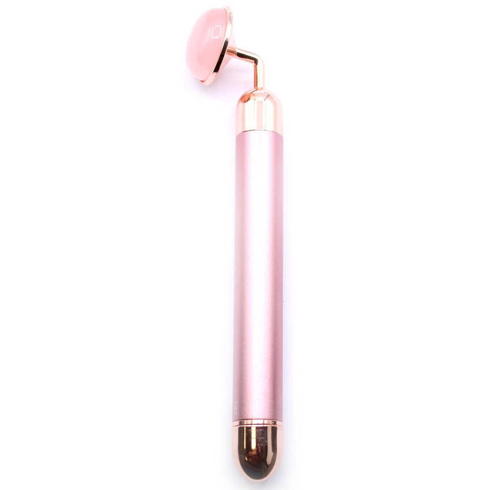 A pink and rose-gold facial roller stands vertically, with a cylindrical handle and a rounded, polished rose quartz rolling head. The tool rests on a clean, white surface.