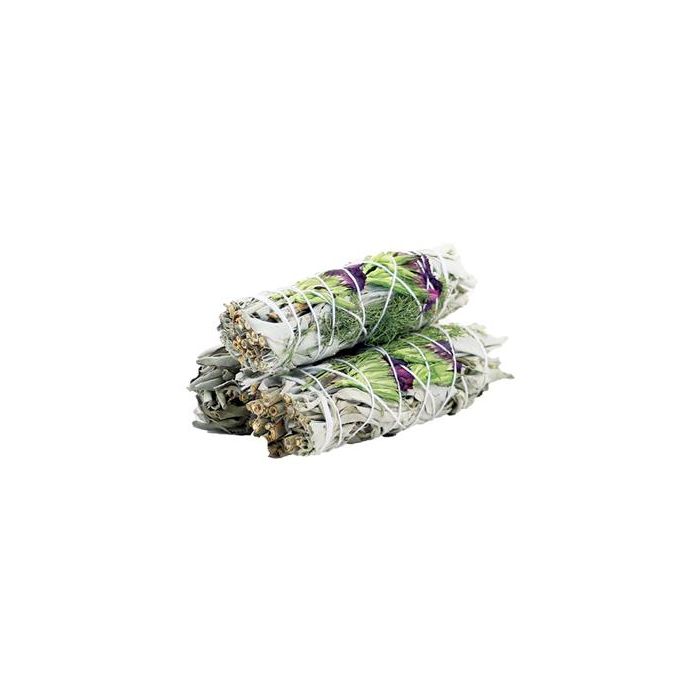 Three smudge sticks of dried herbs, wrapped with white string and some purple flowers, sit stacked upon each other against a white background.