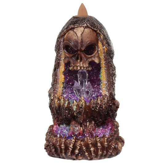 Skull-shaped incense holder with vibrant purple crystals inside, positioned upright. The skull has detailed carvings, and the crystals create a mystical ambiance. The context is a plain white background.