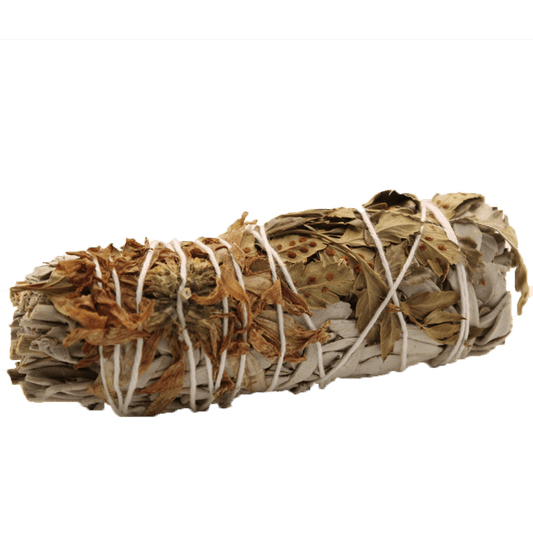 A bundle of dried sage is held together by white string. It sits horizontally against a solid green background.