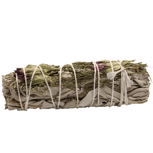Sage bundle is tied with string; it lies on a green background. It is decorated with bits of thin foliage and tiny rose petals.