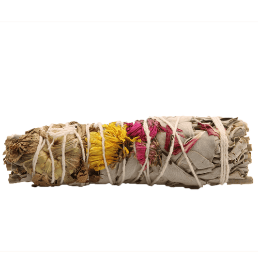A sage bundle with dried flowers is tied with string. It lies horizontally against a plain green background.