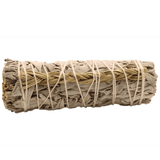 A bundle of dried sage is tightly bound with white string and braided straw. It sits against a solid, dark green background.