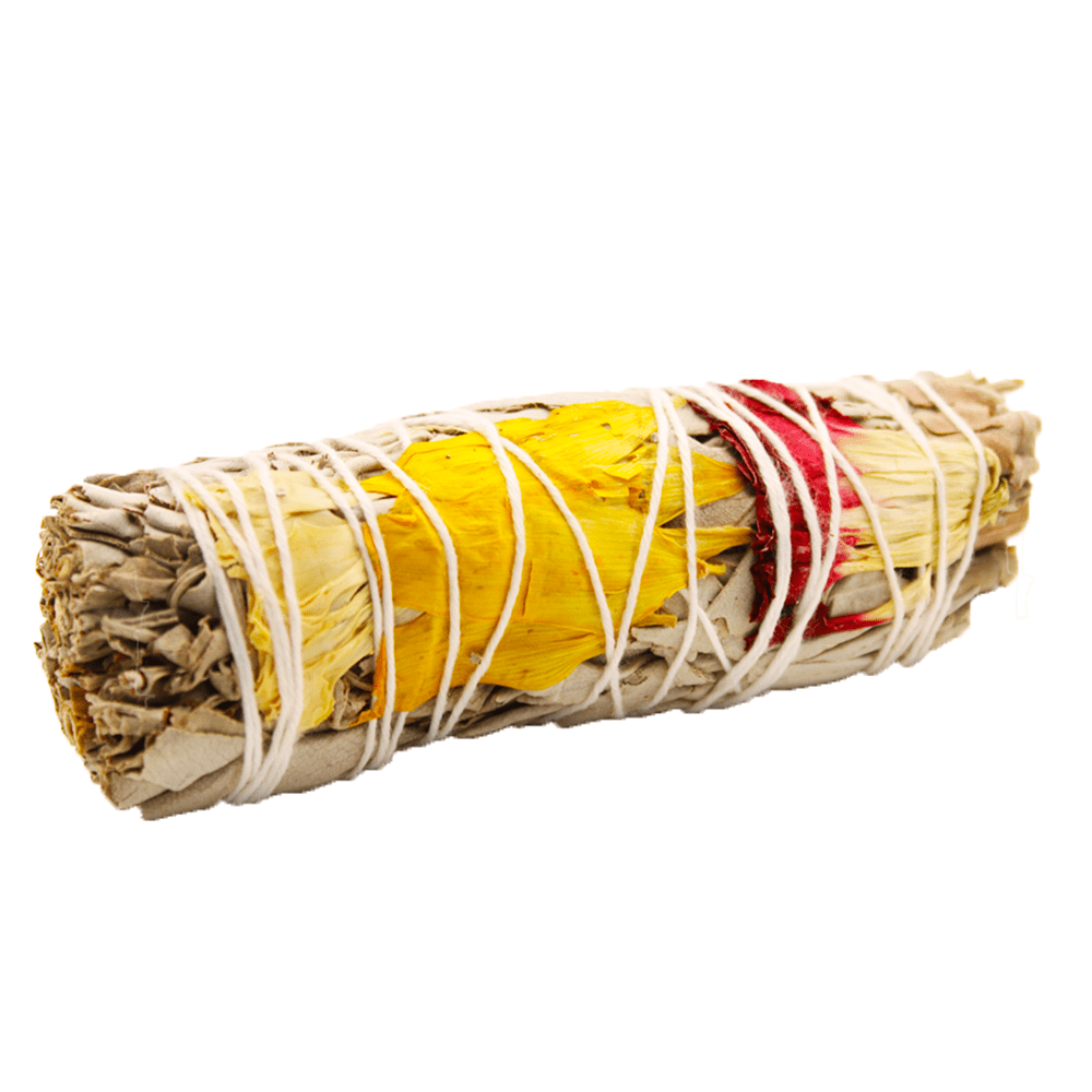 A sage bundle, wrapped with white string, is adorned with yellow and red flower petals. It's isolated against a white background.