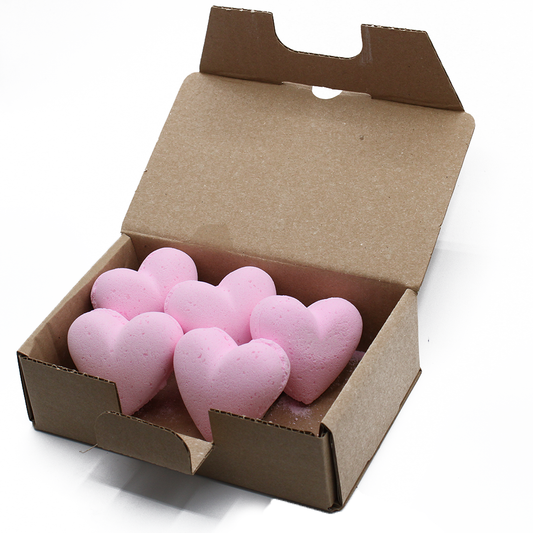 Pink heart-shaped bath bombs are neatly arranged in an open cardboard box, set against a plain white background.