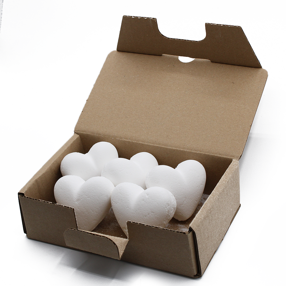White heart-shaped objects are neatly arranged in an open, brown cardboard box. The scene is set against a plain white background, emphasizing the packaging's simplicity and shape.