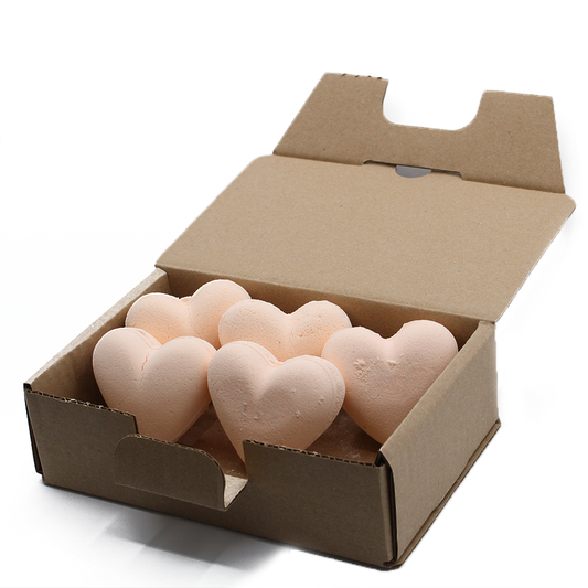 Heart-shaped objects rest inside an open cardboard box. The objects are light pink and arranged neatly within a plain, unmarked package on a white surface.