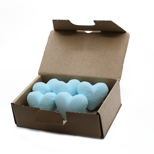 Five blue, heart-shaped bath bombs sit inside an open brown cardboard box against a plain white background.