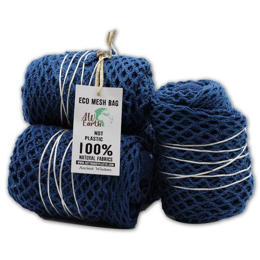 Blue mesh bags, wrapped with white string, are stacked on a white surface. A tag reads, "ECO MESH BAG," "AW Earth," "NOT PLASTIC," "100% NATURAL FABRICS WWW.COTTONNOTPLASTIC.COM Ancient Wisdom."