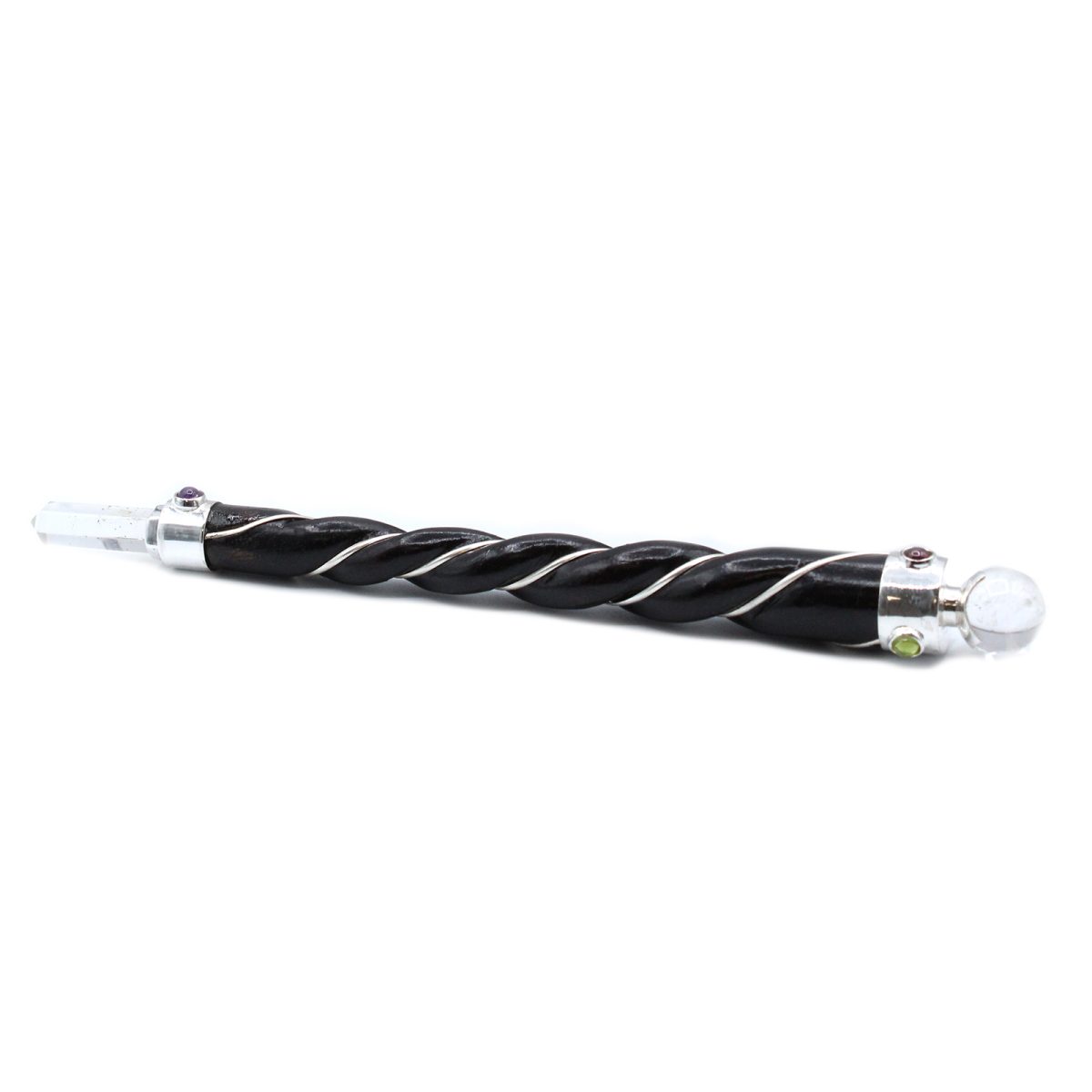 A dark, twisted wand with silver accents lies horizontally on a white surface. Crystals adorn each end of the wand.
