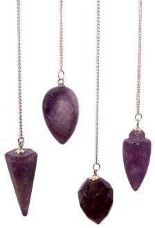Four amethyst pendulums hang from silver chains in a simple white space. The pendulums vary in shape, ranging from conical to teardrop.