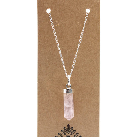 A necklace with a silver chain and light pink crystal hangs on brown cardstock with a leafy pattern.