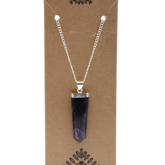 A silver chain holds a pointed amethyst pendant, displayed on a brown cardboard with decorative floral elements.
