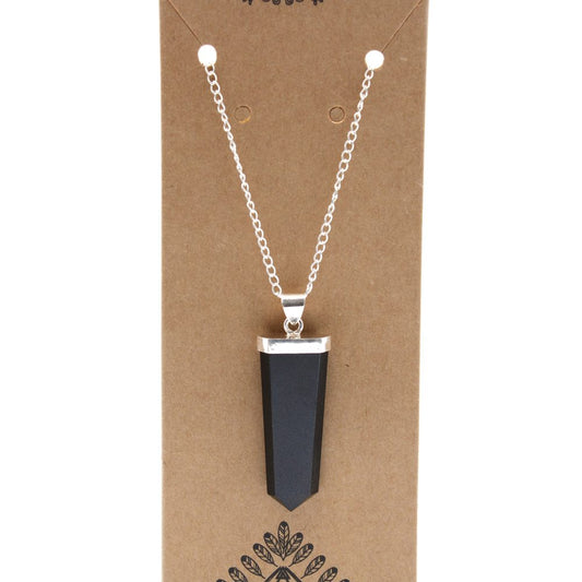 A necklace with a black, pointy pendant hangs on a brown cardboard display. The chain is silver and the top of the pendant is capped with silver.