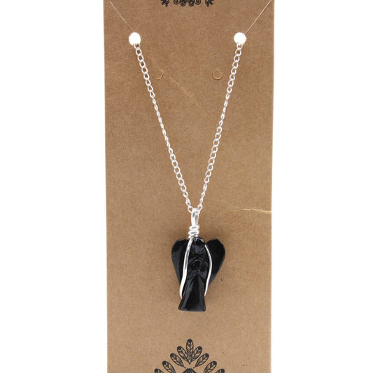 A black, crystal angel pendant hangs from a silver chain, which is attached to a brown cardboard display with decorative plant and flourish elements.