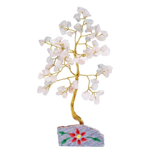 A decorative gemstone tree stands on a stone base with a red flower. Its twisted gold wire branches hold clear quartz chips, resembling leaves, against a white background.