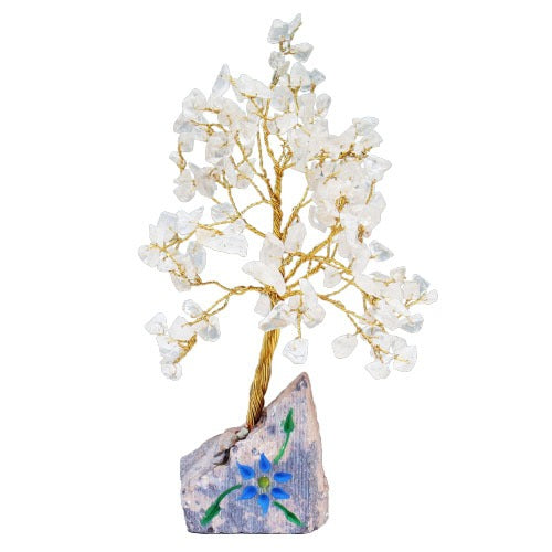 A small crystal tree with a twisted gold wire trunk sits upon a rectangular stone base adorned with a blue flower and green leaves. The leaves are made of translucent crystals.