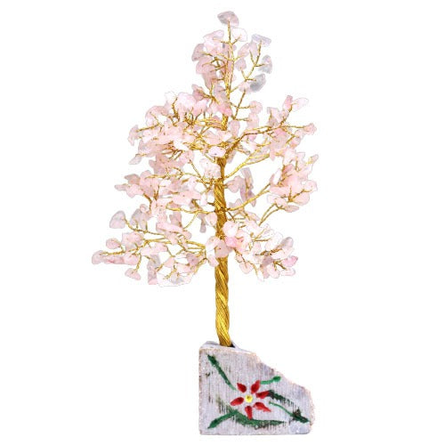 A small, decorative wire tree "grows" pink crystal leaves on a gold trunk from a base of rough-cut stone painted with a red flower and green leaves. The tree is on a white background.