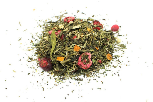 A pile of loose-leaf herbal tea includes dried green leaves, red berries, and orange peels, scattered on a white background.