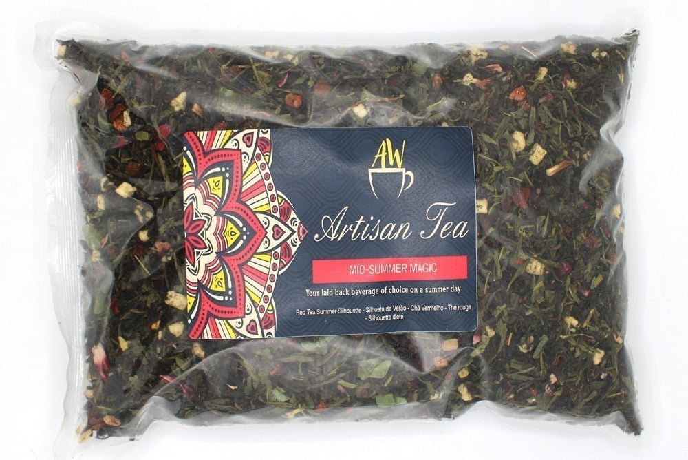 A sealed bag contains loose-leaf tea labeled "Artisan Tea, MID-SUMMER MAGIC." The label features a colorful mandala design. Text reads: "Your laid back beverage of choice on a summer day. Red Tea Summer Silhouette - Silhouette de Verão - Chá Vermelho - Thé rouge - Silhouette d'été."