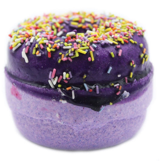 A purple doughnut-shaped bath bomb with multi-colored sprinkles on top sits against a plain white background.