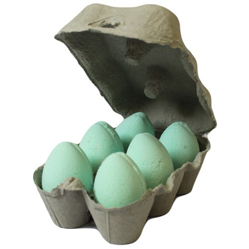 Carton containing six light blue eggs, open and positioned at an angle. The eggs are neatly arranged in a gray, cardboard egg carton against a white background.