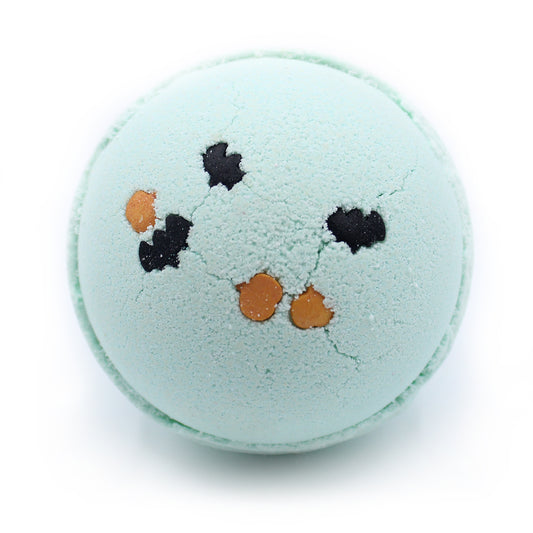 A round, light blue bath bomb with small black and orange shapes on its surface, rests against a white background.