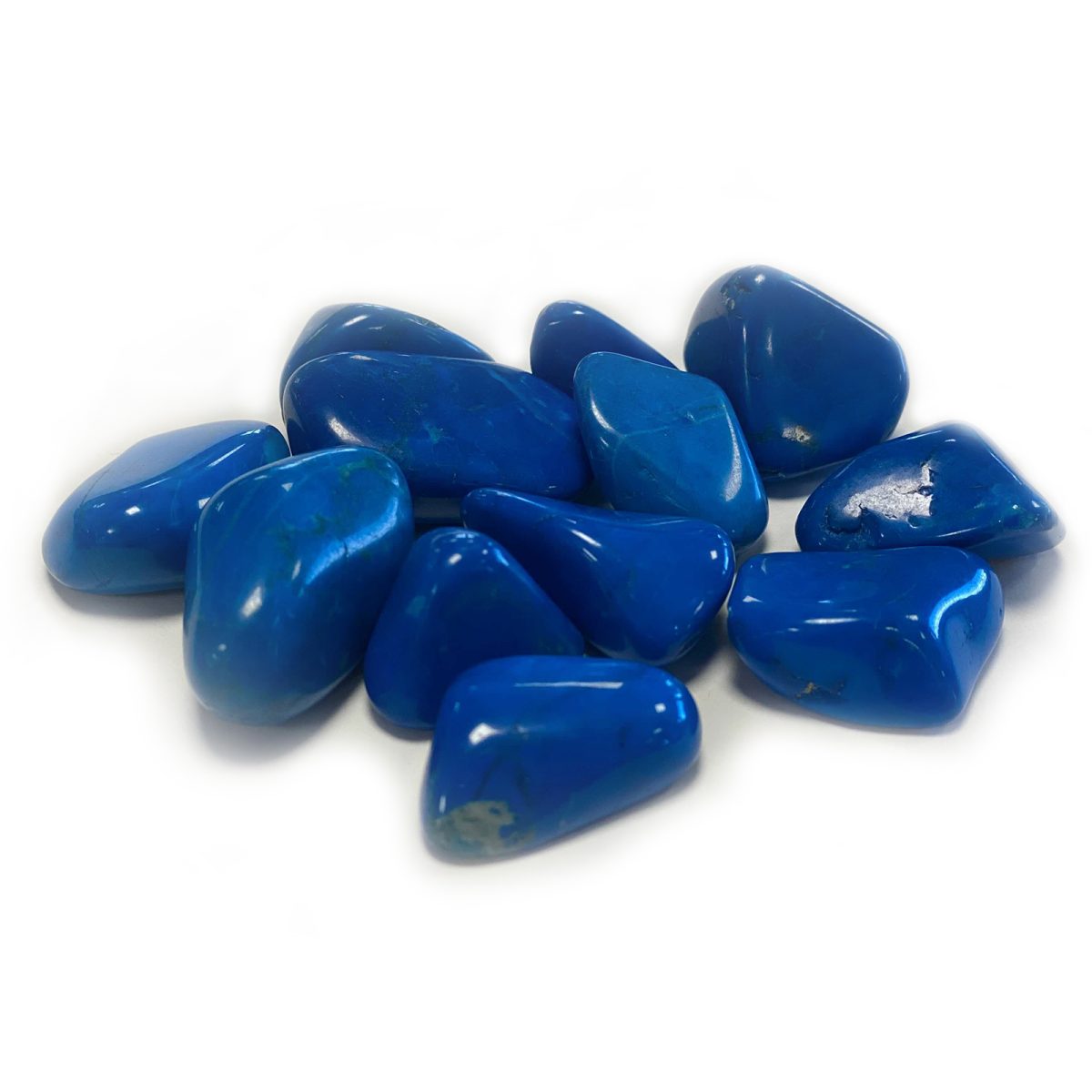 A pile of highly polished, dark-blue stones sit clustered together on a white surface. Some stones reflect light in spots.