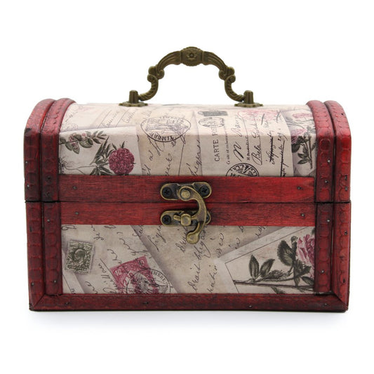 A small, decorative chest with vintage postal designs and red wooden accents sits closed, ornate metal handle on top, and brass latch at the front, set against a plain background.