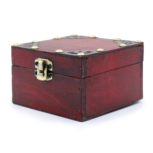 A small wooden box, featuring a brass latch and decorative metal studs, rests closed on a white surface. Its dark reddish-brown color suggests an antique style.