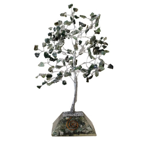 A decorative tree with silver wire branches and gemstone leaves sits on a speckled green base with a copper spiral. The background is white.