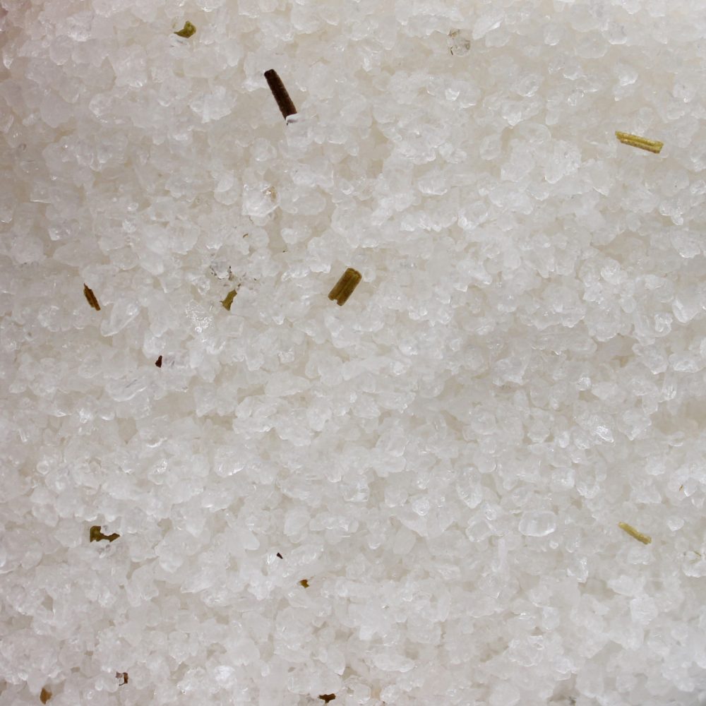 Salt crystals sit interspersed with tiny herbs. The scene provides a close-up shot of the mixture in a square frame.
