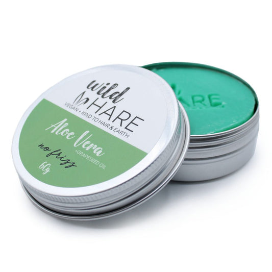 Metal tin of green aloe vera hair pomade sits open on a white background; label reads: wild HARE VEGAN + KIND TO HAIR & EARTH Aloe Vera no frizz *GRAPESEED OIL 60g and HARE embossed on the product surface