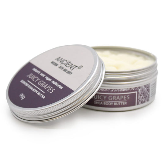 Tin of Juicy Grapes shea body butter with lid resting beside an open metal tin revealing pale cream on a white background; text reads: ANCIENT®, JUICY GRAPES, SHEA BODY BUTTER, 90g.