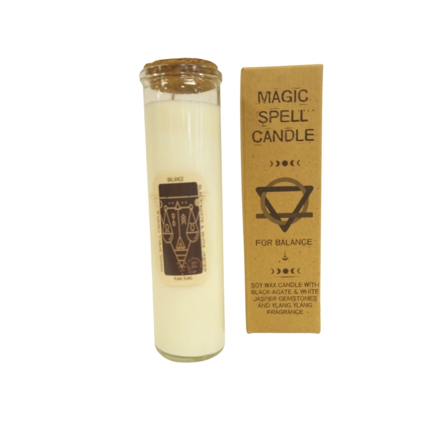 A white candle in a glass container with a cork lid sits next to a small, brown box that reads: "MAGIC SPELL CANDLE" and "FOR BALANCE. SOY WAX CANDLE WITH BLACK AGATE & WHITE JASPER GEMSTONES AND YLANG YLANG FRAGRANCE".