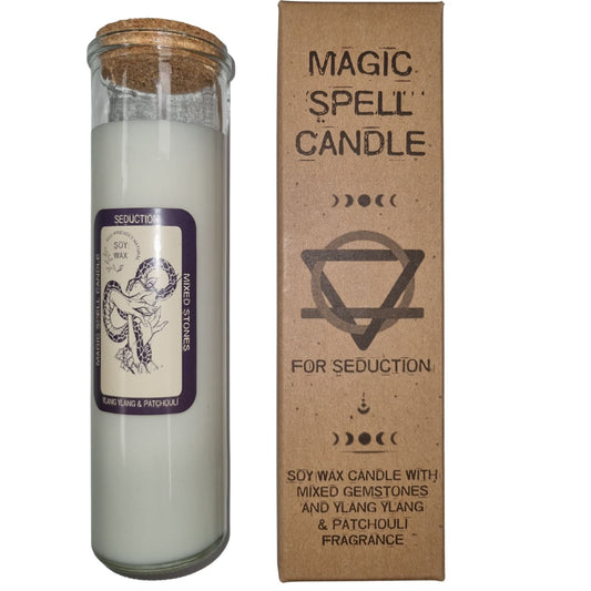 Tall glass candle sits beside its cardboard box on a white background; text on box: MAGIC SPELL CANDLE FOR SEDUCTION SOY WAX CANDLE WITH MIXED GEMSTONES AND YLANG YLANG & PATCHOULI FRAGRANCE; text on candle label: SEDUCTION SOY WAX ECO-FRIENDLY NATURAL MAGIC SPELL CANDLE MIXED STONES YLANG YLANG & PATCHOULI