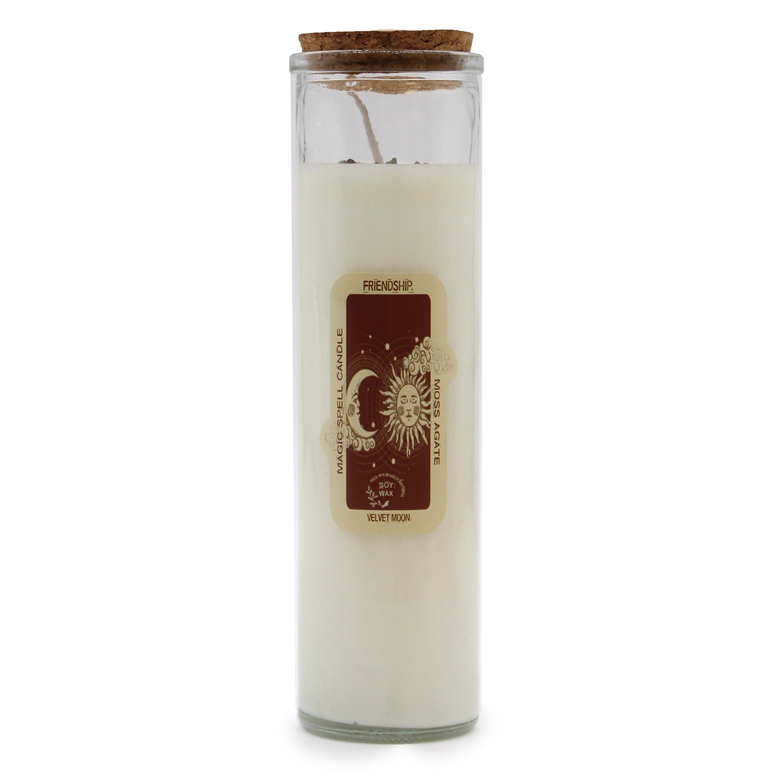 A cylindrical candle sits on a white surface, featuring a cork lid. Its label reads "FRIENDSHIP." above “MAGIC SPELL CANDLE MOSS AGATE ECO-FRIENDLY NATURAL SOY WAX VELVET MOON” along with a sun and moon design.