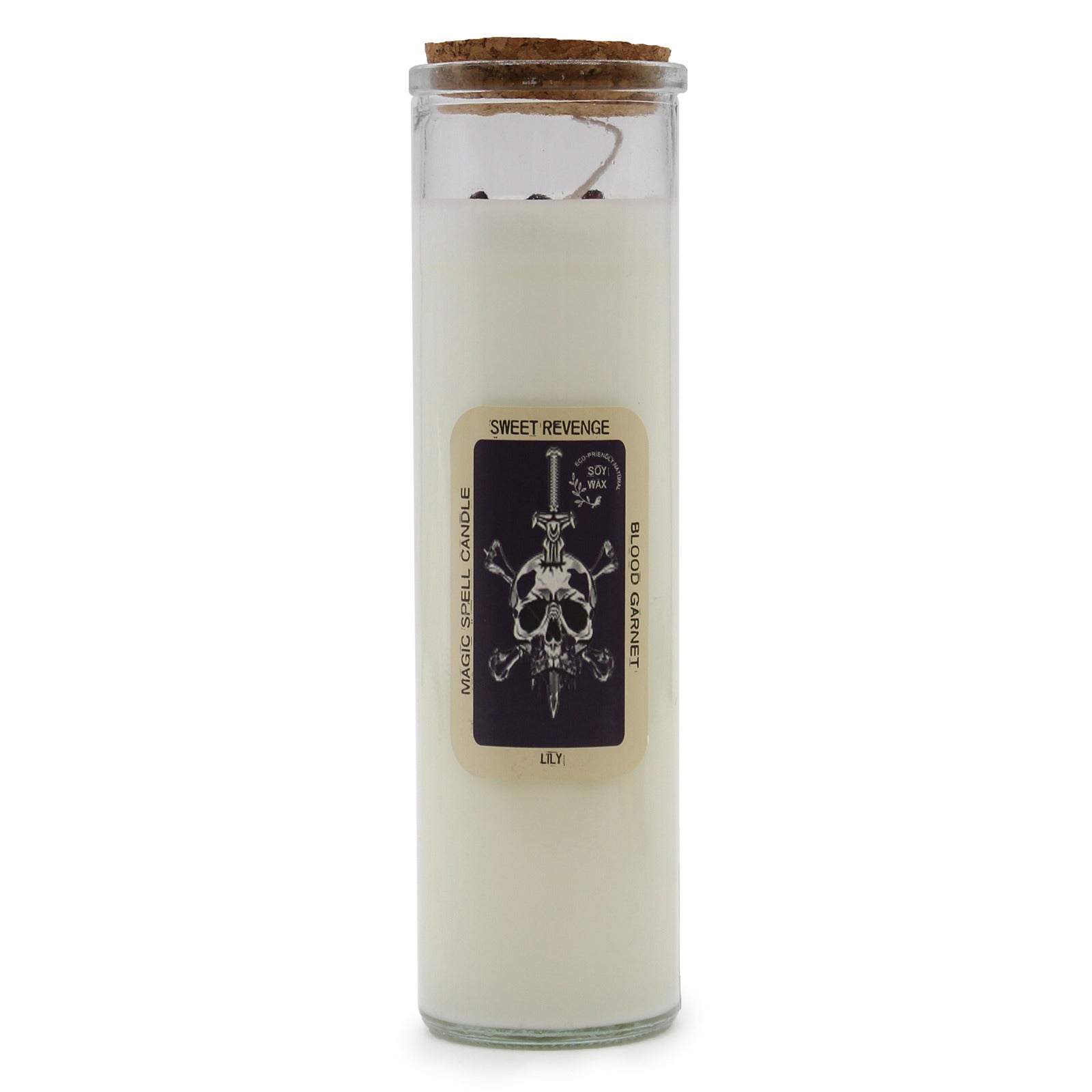 A white candle with a cork lid stands on a white surface; its label reads "MAGIC SPELL CANDLE", "SWEET REVENGE", "ECO-FRIENDLY SOY WAX", "BLOOD GARNET", and "LILY" with a skull and sword design.