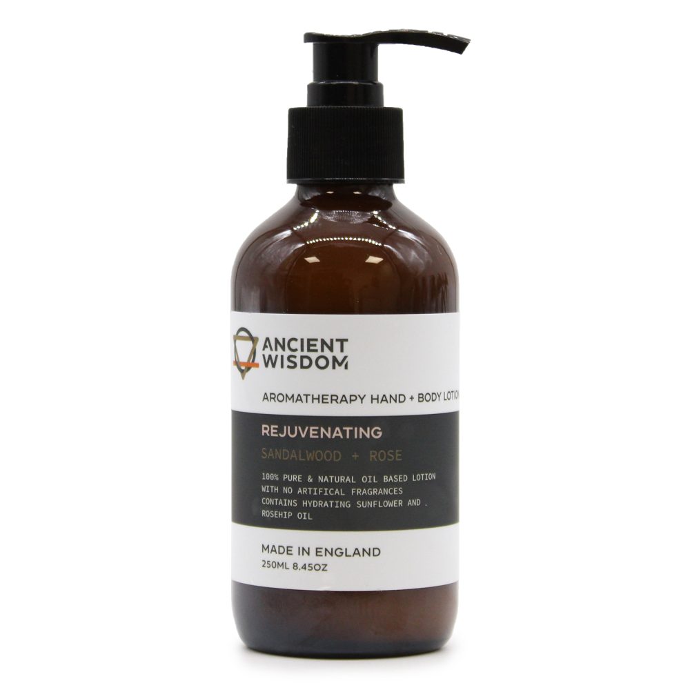 A brown bottle of Ancient Wisdom aromatherapy hand and body lotion sits on a white background. The lotion is labeled "Rejuvenating Sandalwood + Rose". It's made in England.