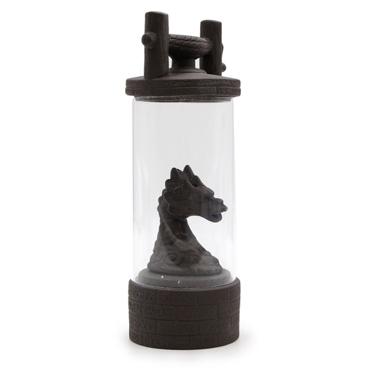 A dragon-head sculpture is enclosed in a cylindrical glass container with decorative handles. The base and lid resemble castle stonework, enhancing the fantasy theme.