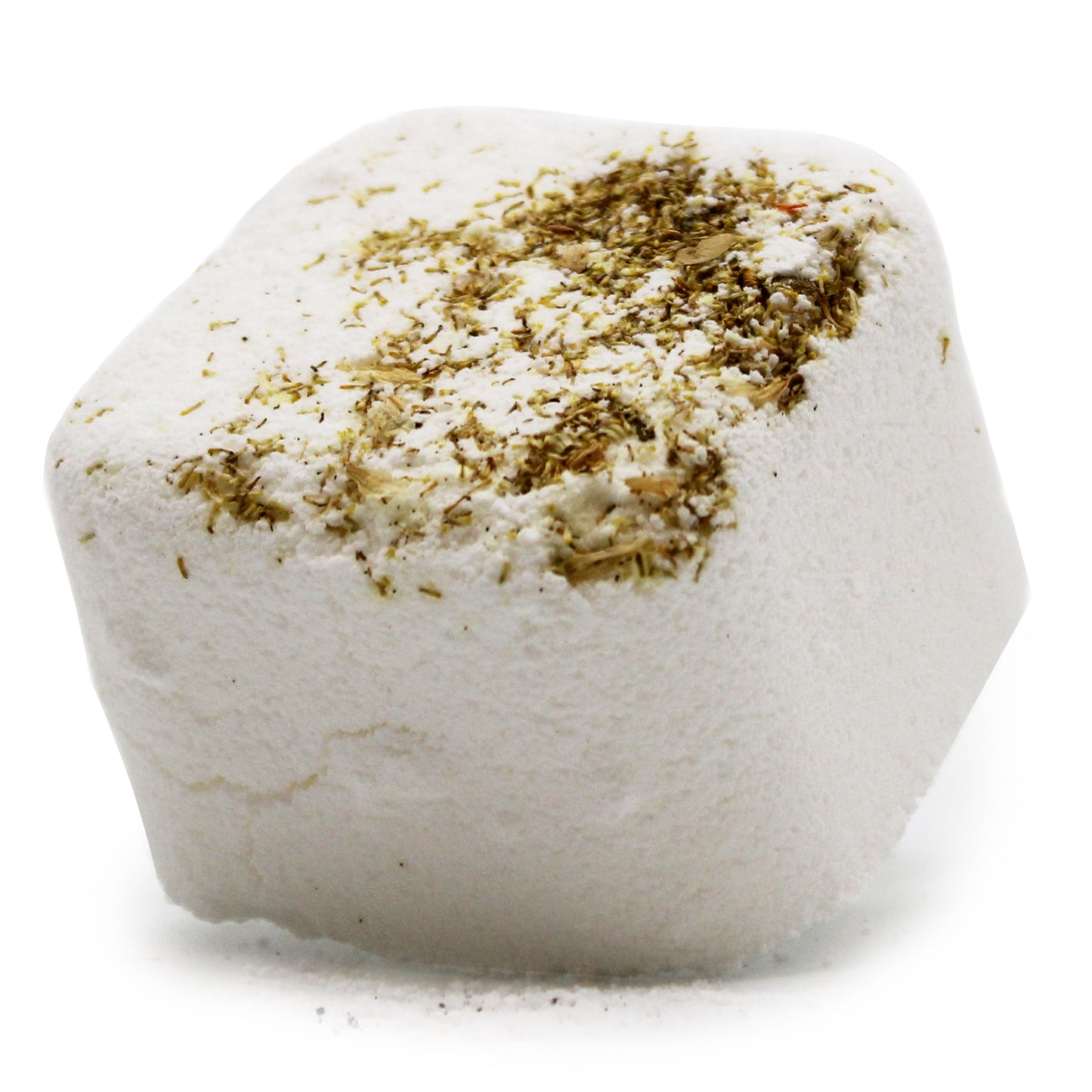 A white, hexagonal bath bomb is resting on a surface. It is topped with dried herbs, providing a textured contrast to its smooth body.
