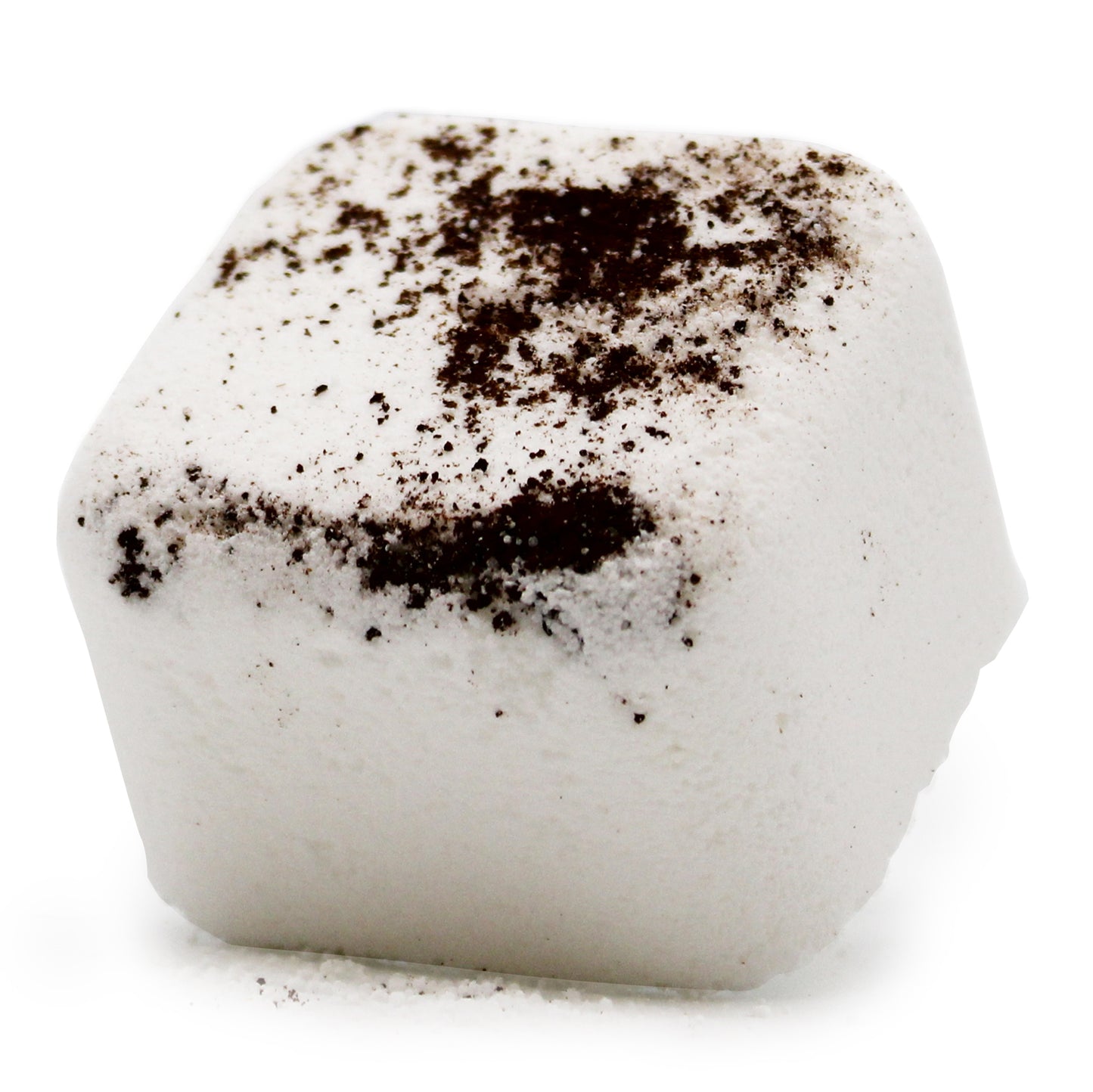 A white, cube-shaped bath product with dark specks scattered on its surface, resting on a smooth, plain background.