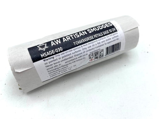A smudge stick rests on a white surface; a black and white label is wrapped around it reading "AW ARTISAN SMUDGES, MSAGE-030 7 CHAKRASROSE PETALS SAGE 10 CM." Warning and company information follow.