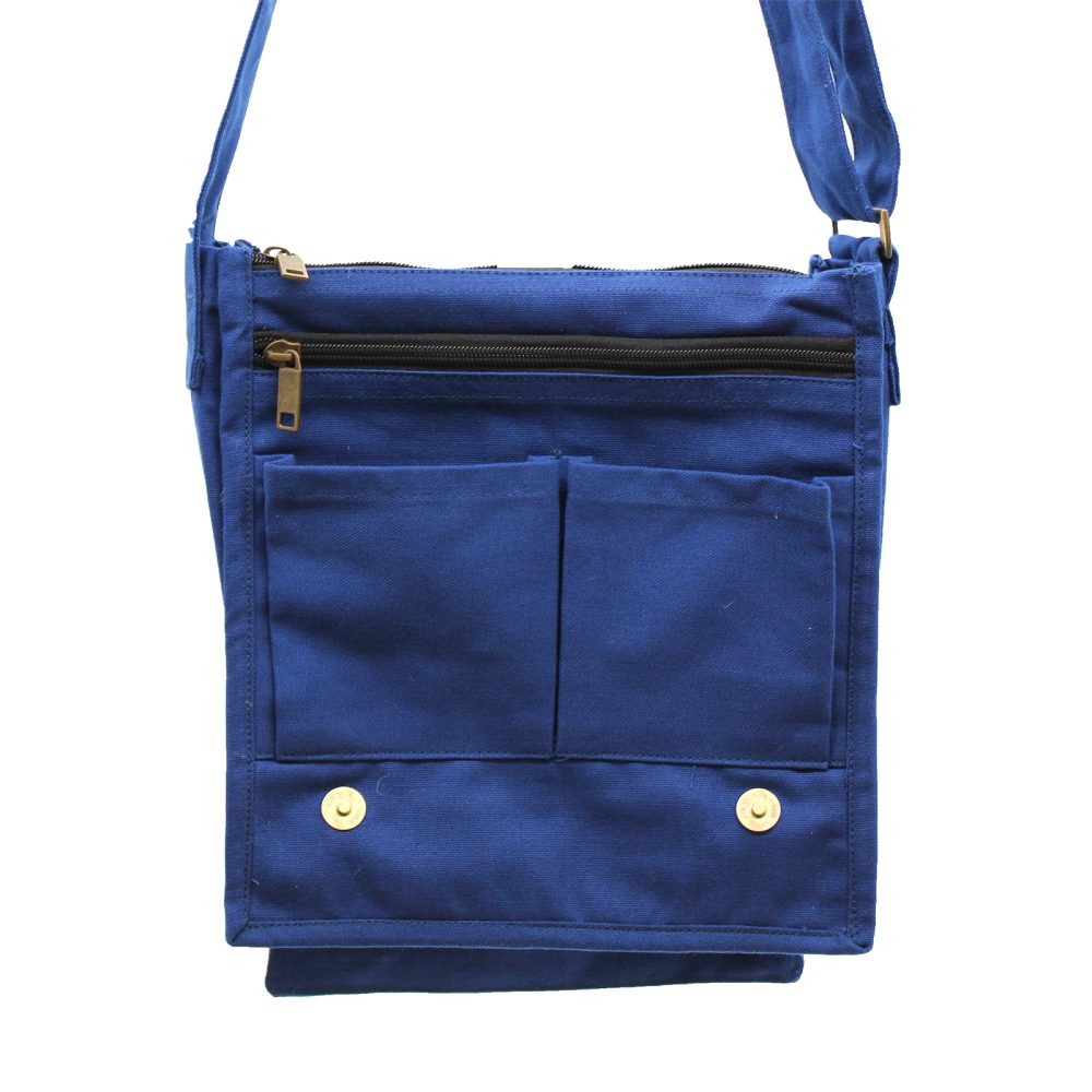A blue, cotton canvas cross-body bag is displayed. The bag features a zippered top, two front pockets, and a flap closure with two gold snaps. The background is white.