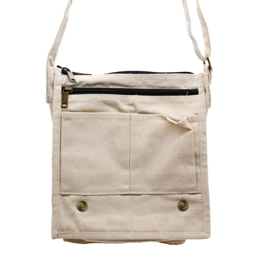 The tan canvas messenger bag hangs, featuring two zipped compartments and two open pockets on the front, fastened with two snap buttons. The background is white.